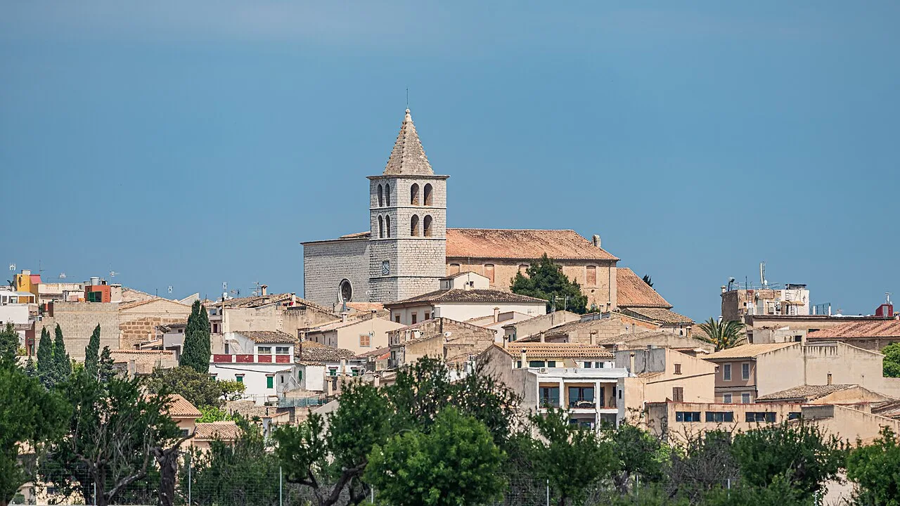 View over the rooftops of Campanet, with the church tower against a blue sky.